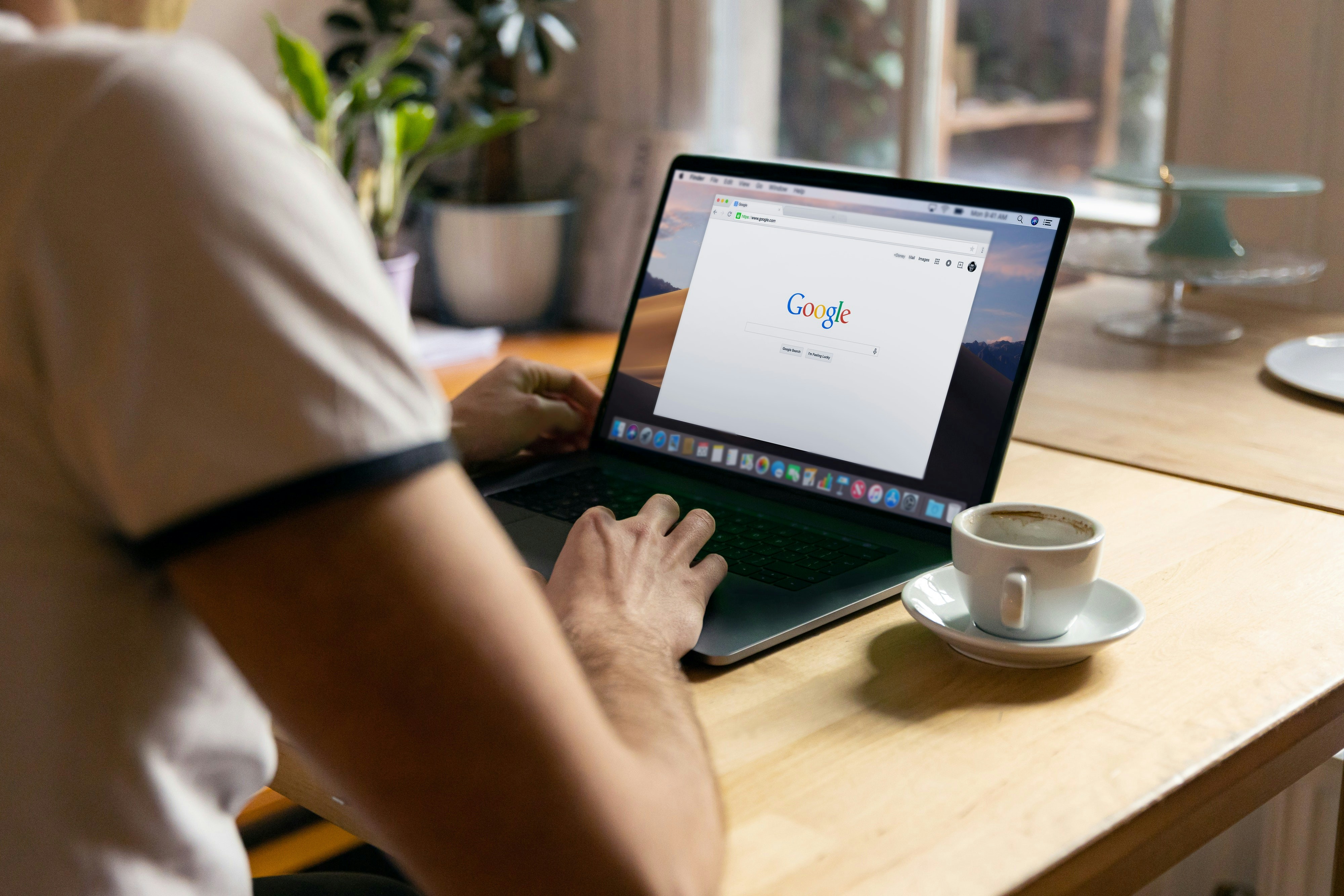 Kuvassa ihmisen kädet tietokoneen näppäimistöllä ja ruudulla näkyy Google-sivut